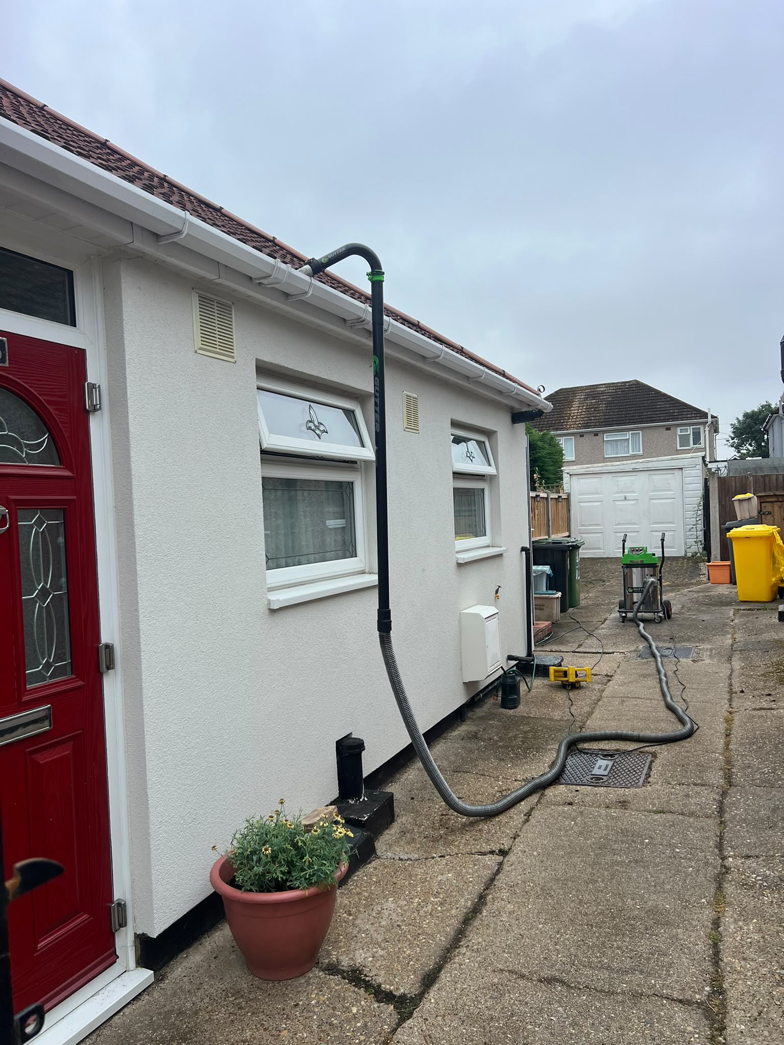 Gutter vacuum pole and hose reaching the gutter on a bungalow